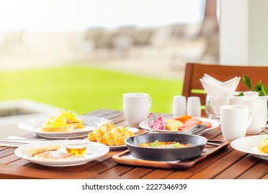 Healthy breakfast in outdoors cafe. Fresh bakery on plate on the wooden table full of various colorful food on lunch time - eggs Benedict, Shakshuka, tropical fruits. Hotel morning. - Powered by Shutterstock