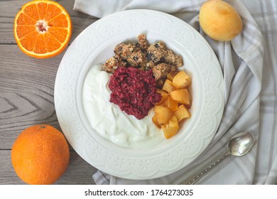 Healthy Breakfast Parfait Of Granola, Greek Yogurt, Apricot And Raspberry Chia Jam In A Bowl. Fruits In The Back