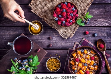 Healthy breakfast with pumpkin porridge, berries and herbal tea with honey at village summer house