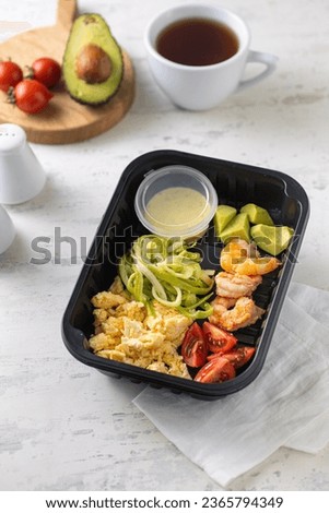 Healthy breakfast with scramble eggs, avocado and zucchini food in box. Fresh box . lifestyle, day meal plan. Vertical
