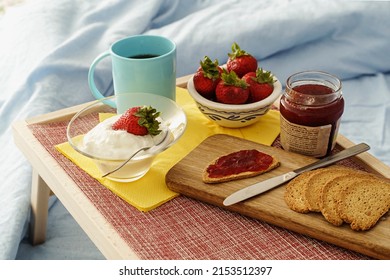 Healthy breakfast served in bed - tray with fruit, yogurt, juice and coffee to eat between the blankets - healthy lifestyle concept - no people