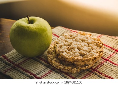 A healthy breakfast, a healthy snack, an apple and two multigrain breads on the table.