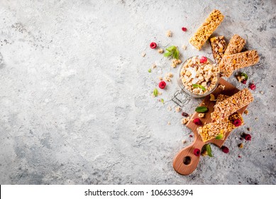 Healthy breakfast and snack concept, homemade granola with fresh raspberries in jar and nuts and granola bars, on grey stone stone background copy space top view - Powered by Shutterstock