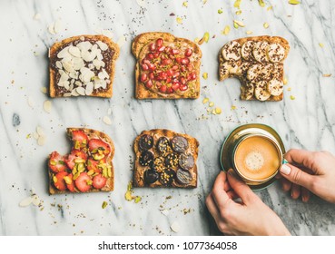 Healthy breakfast, snack. Flat-lay of vegan wholegrain toasts with fruit, seeds, nuts, peanut butter, cup of espresso and woman hands over light marble background, top view. Clean eating food concept