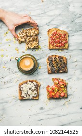 Healthy Breakfast, Snack. Flat-lay Of Vegan Wholegrain Toasts With Fruit, Seeds, Nuts, Peanut Butter, Cup Of Espresso And Woman Hand Over Marble Background, Top View. Clean Eating Food Concept