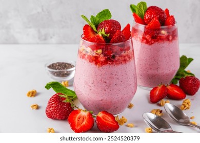 Healthy breakfast. Strawberry yogurt parfait with chia seeds topped with fresh strawberries, granola and mint in glasses with spoons on white background. Strawberry chia pudding. Tasty food - Powered by Shutterstock