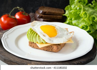 Healthy breakfast, sunny side up egg on whole grain toast with sliced avocado and cheese - Powered by Shutterstock