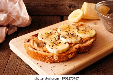 Healthy breakfast toast with peanut butter, bananas and chia seeds on multi grain bread. Close up on a dark wood background. - Powered by Shutterstock