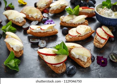 Healthy breakfast toasts with cottage cheese and nectarine slices, sprinkled with cinnamon, served with dark grapes and edible flowers - Powered by Shutterstock