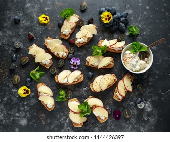 Healthy breakfast toasts with cottage cheese and nectarine slices, sprinkled with cinnamon, served with dark grapes and edible flowers - Powered by Shutterstock