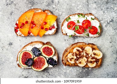 Healthy breakfast toasts with peanut butter, banana, chocolate granola, cream cheese, figs, blackberry, persimmon, pomegranate, chia seeds, tomato, micro greens. Top view, overhead