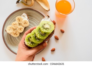 Healthy breakfast toasts. Wholegrain bread slices with coconut yogurt, kiwi ,banana,sesame and nuts. Top view, white background. Clean eating, vegetarian, dieting concept