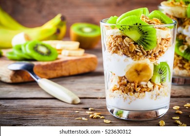 Healthy Breakfast: Yogurt Parfait With Granola, Banana And Kiwi On A Wooden Background