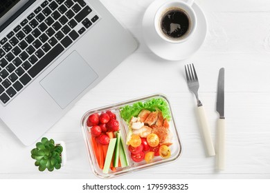 Healthy Business Lunch In Office Workplace. Top View Of Vegetable And Chicken Salad In Lunch Box And Cup Of Coffee On White Wooden Desk Near Laptop.