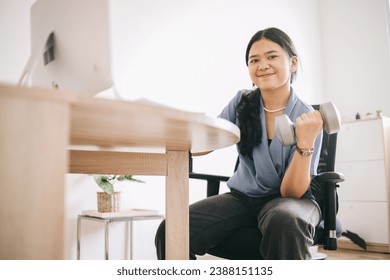 Healthy businesswoman working while doing little workout with dumbbells at office - Powered by Shutterstock