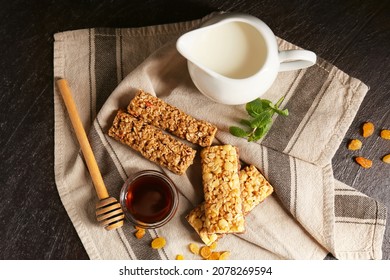 Healthy cereal bars, honey and raisins on dark background