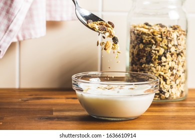 Healthy Cereal Breakfast. Muesli Falling Into A Bowl Of Milk On Wooden Table.