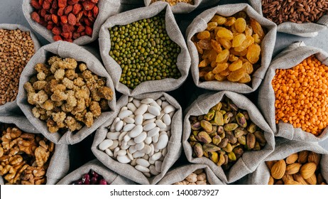 Healthy Cereals And Dried Fruit. Close Up Top View Of Small Bags With Dry Legumes Seeds. Different Types Of Beans. Natural Grains.