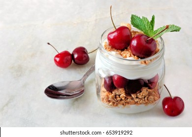 Healthy Cherry Yogurt Parfait In A Mason Jar On A White Marble Background