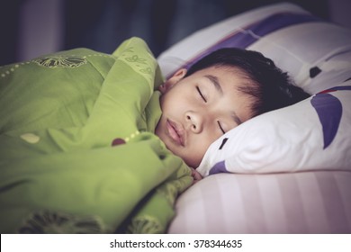 Healthy Child. Little Asian Boy Sleeping Peacefully On Bed In Dark Bedroom. Vintage Picture Style.