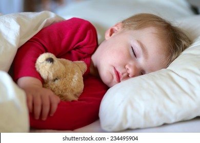 Gesundes Kind, süßeste blonde Kleinkind, die im Bett schläft und ihren Teddybär hält