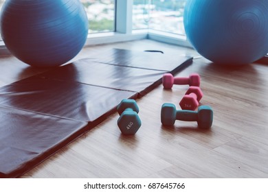 Healthy Concept With Fitness Center Dumbell Rack And Yoga Ball With Exercise Mat On Wooden Floor With Background Of Blue Sky