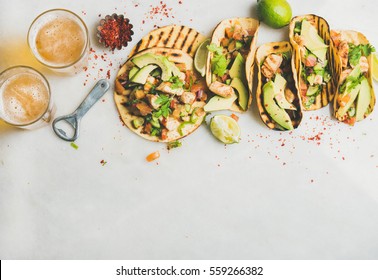 Healthy corn tortillas with grilled chicken, avocado, fresh salsa, limes and beer in glasses over light grey marble table background, top view, copy space. Gluten-free, allergy-friendly food concept - Powered by Shutterstock