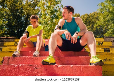 Healthy Couple With Headphones Rest After Running. Staying Fit Concept Urban. Low Angle Pov