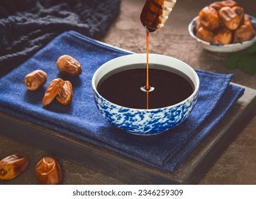 Healthy date syrup with whole and dry pitted dates. Delicious date syrup flows from a wooden honey dipper into a small bowl. It is natural sweetener made with dates. - Powered by Shutterstock