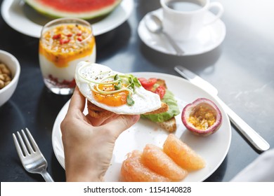 Healthy And Delicious Breakfast. Woman Is Eating Toast With A Fried Egg.