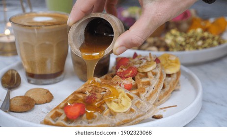 Healthy And Delicious Vegan Breakfast. Close Up Of Hand Pouring Honey On Waffles Served With Dairy Free Coffee Latte. 