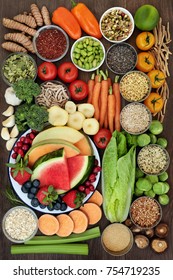 Healthy diet food concept with a selection of fruit, vegetables, seeds, grains, cereals, herbs and spices with foods high in vitamins, minerals, anthocyanins, antioxidants and fibre on oak top view.