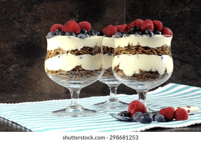 Healthy Diet High Dietary Fiber Breakfast Sundaes With Bran Cereal, Yogurt And Berries Trifles On Black Slate Kitchen Bench Top.