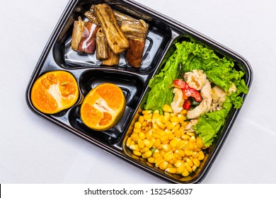 Healthy diet meal plan with corn, shredded chicken, veggies and oranges in bento box top view - Powered by Shutterstock