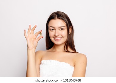 Healthy Diet Nutrition. Beautiful Smiling Young Woman Holding Fish Oil Pill In Hand. Closeup Of Happy Girl Taking Capsule With Cod Liver Oil, Omega-3. Vitamin And Dietary Supplements. High Resolution