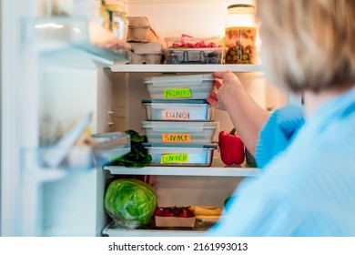 Healthy diet plan for weight loss, daily ready meal menu. Woman taking or putting breakfast box cooked in advance, ready to be served into fridge. Containers with eco healthy food. Pre-cooking concept