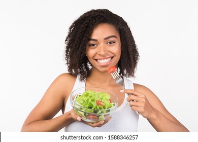 Healthy Diet. Portrait of african american woman eating salad, smiling at camera isolated on white background - Shutterstock ID 1588346257