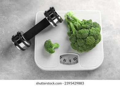 Healthy diet. Scale, broccoli and dumbbell on grey table, top view - Shutterstock ID 2395429883