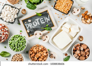 Healthy diet vegan food, veggie protein sources: Tofu, vegan milk, beans, lentils, nuts, soy milk, spinach and seeds. Top view on white table. - Shutterstock ID 1008838606