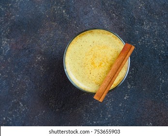 Healthy drink golden turmeric latte in glass.Gold milk with turmericy on black cement background. Detox turmeric tea with copy space. Top view or flat-lay