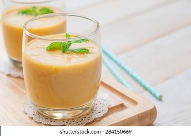 Healthy drink mango smoothies with mint on wooden background