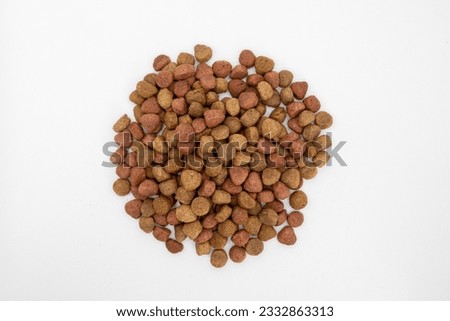 Healthy dry pet food for dogs and cats. Dry pets food on a white background. Brown crunchy kibble pieces for pets feed heap isolated on white background.