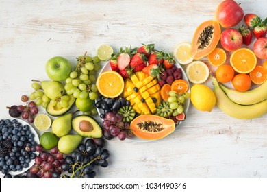 Healthy eating background, assortment of fruits and vegetables in rainbow colours on the off white table arranged diagonally, copy space, top view, selective focus