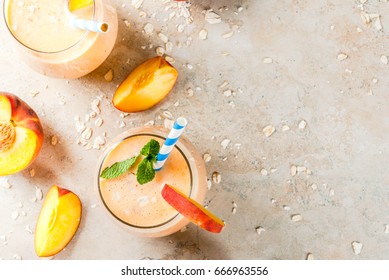 Healthy eating. Breakfast, snack. Drink smoothies from fresh peach, milk (yogurt) and oatmeal, decorated with mint leaves, with striped straws. On a light stone table. Copy space top view 