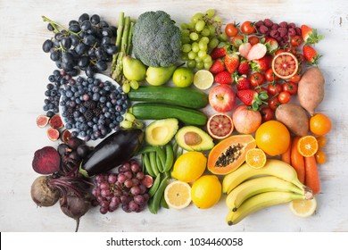 Healthy eating concept, assortment of rainbow fruits and vegetables, berries, bananas, oranges, grapes, broccoli, beetroot background on white table arranged in rectangle, top view, selective focus - Powered by Shutterstock