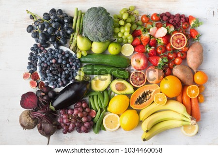 Healthy eating concept, assortment of rainbow fruits and vegetables, berries, bananas, oranges, grapes, broccoli, beetroot background on white table arranged in rectangle, top view, selective focus