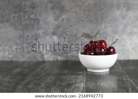 healthy eating concept - black cherries in a bowl isolated on gray background