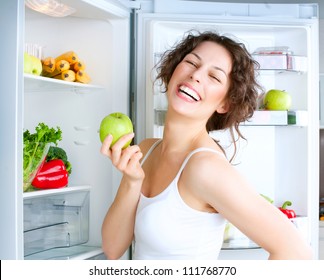 Healthy Eating Concept .Diet. Beautiful Young Woman near the Refrigerator with healthy food. Fruits and Vegetables in a Fridge