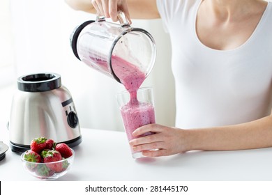 healthy eating, cooking, vegetarian food, dieting and people concept - close up of woman with blender and strawberries pouring milk shake to glass at home - Powered by Shutterstock