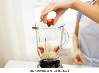 Healthy Eating, Cooking, Vegetarian Food, Diet And People Concept - Close Up Of Woman With Blender Making Banana Strawberry Fruit Shake At Home